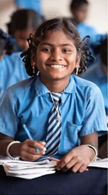 A smiling girl writing in her notebook at school